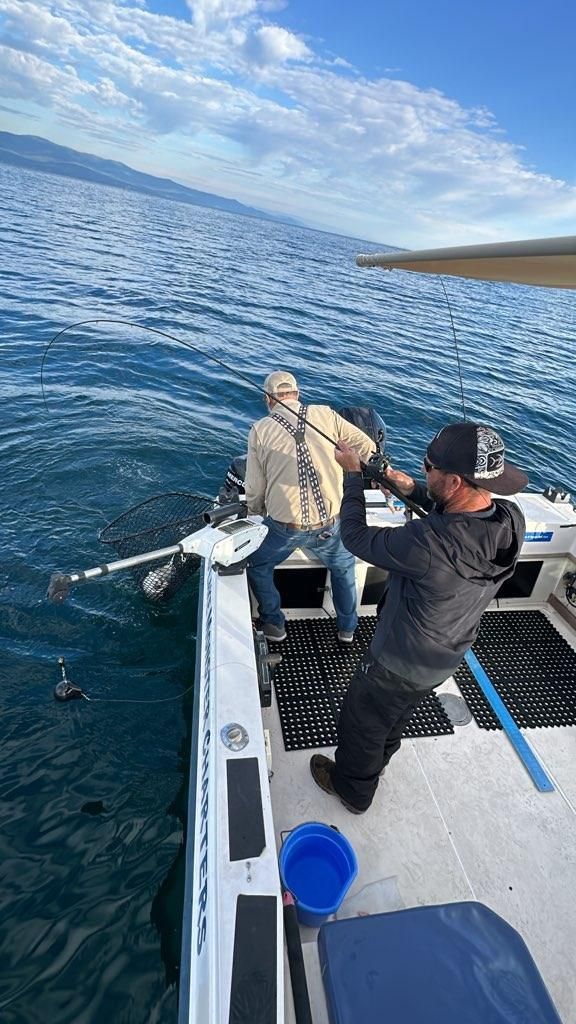 Two men are fishing on a boat in the ocean.