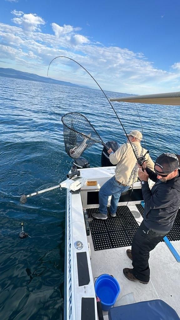 Two men are fishing on a boat in the ocean.
