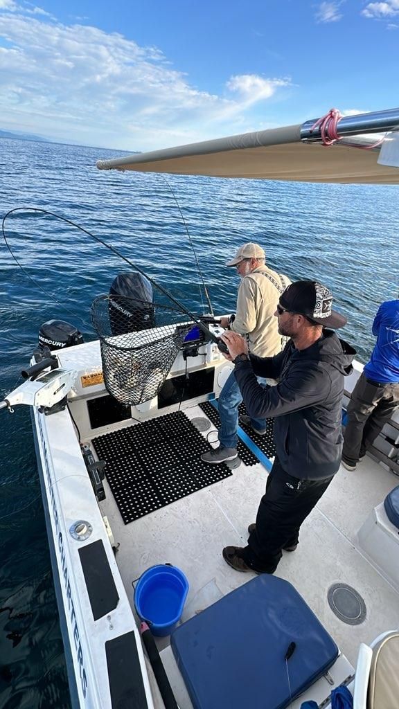 Two men are fishing on a boat in the ocean.
