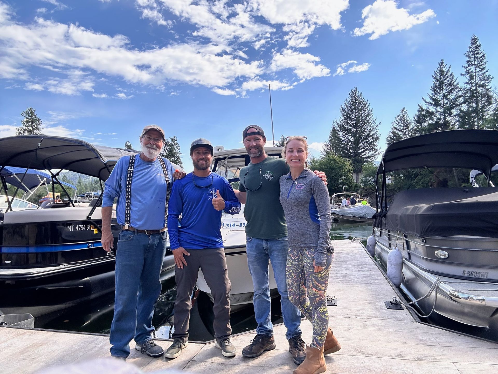A group of people are posing for a picture in front of boats.