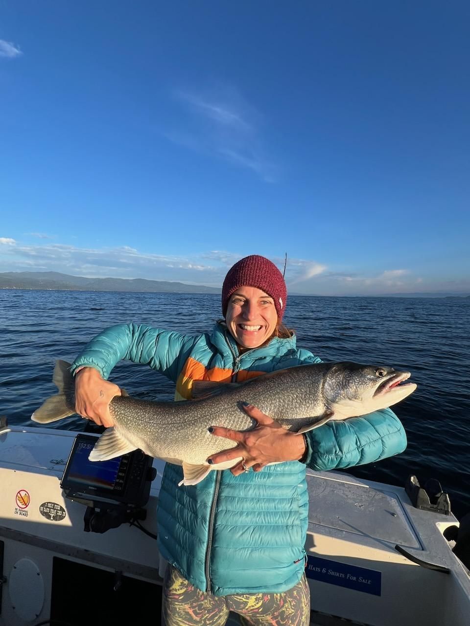 A woman is holding a large fish on a boat.