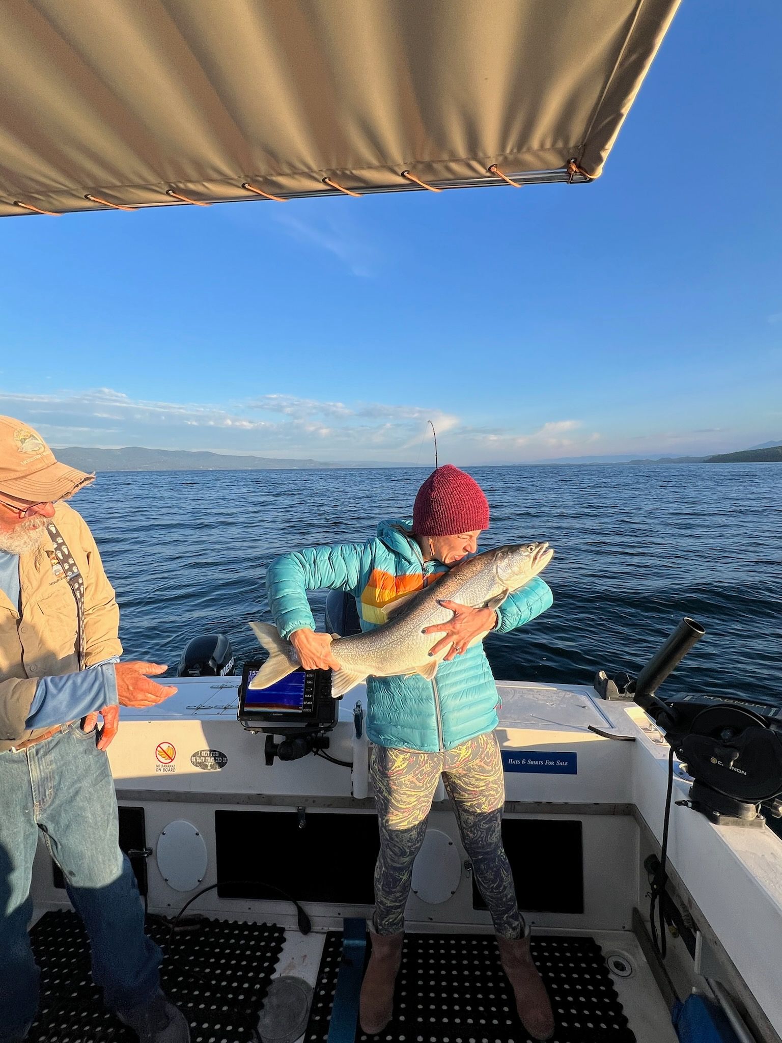 A woman is holding a fish on a boat in the ocean.