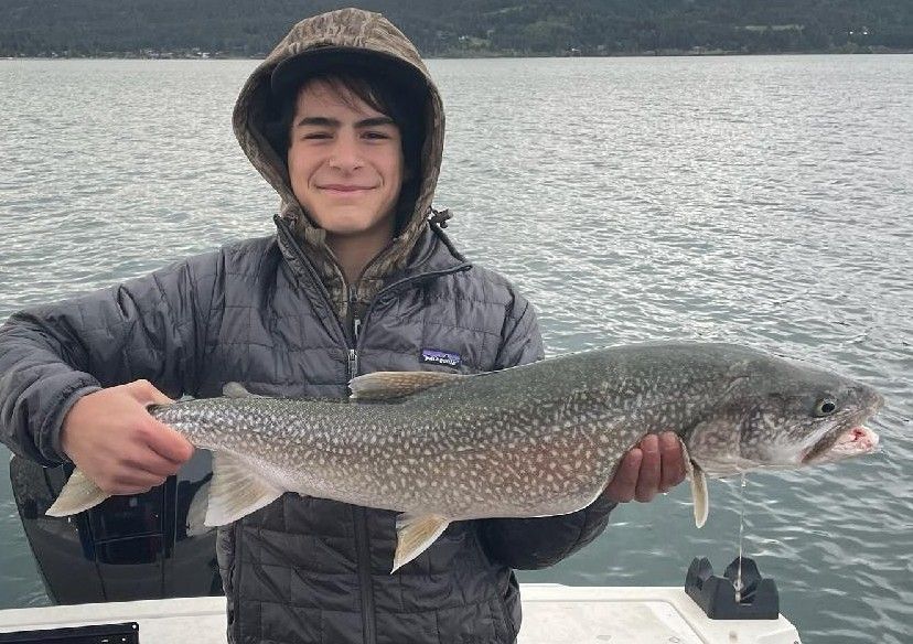 A young man is holding a large fish on a boat.