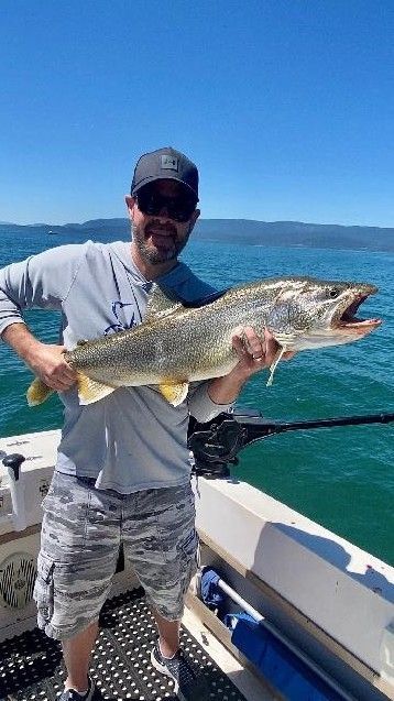 A man is holding a large fish on a boat.