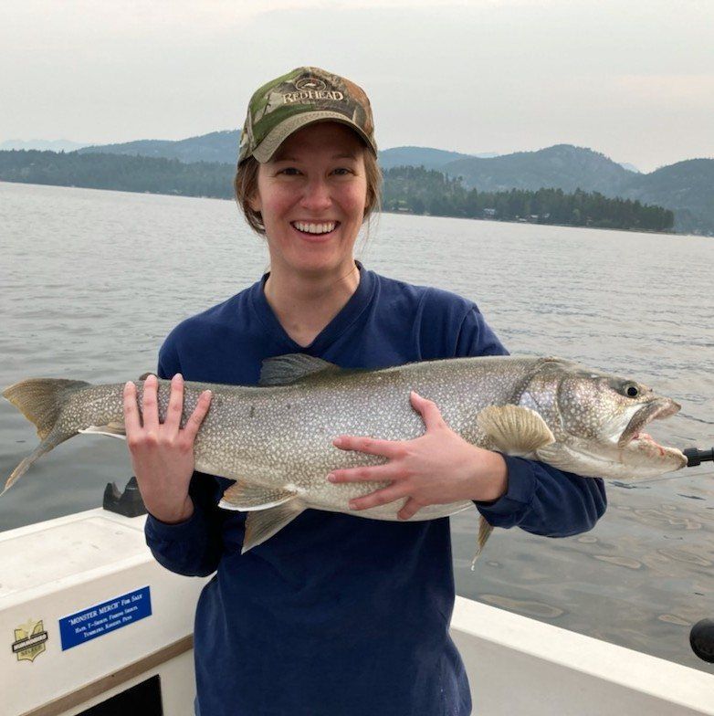 A woman is holding a large fish on a boat