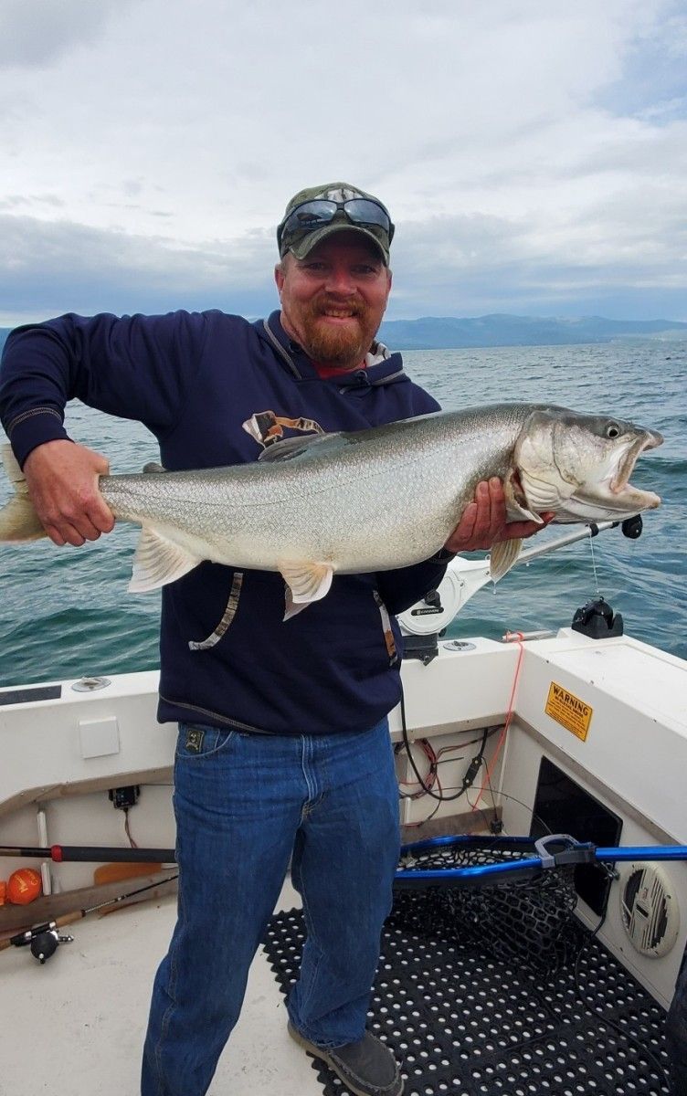 A man is holding a large fish on a boat.