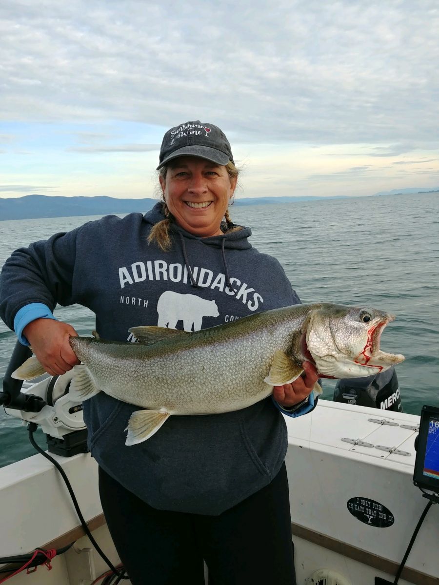 A woman is holding a large fish on a boat.