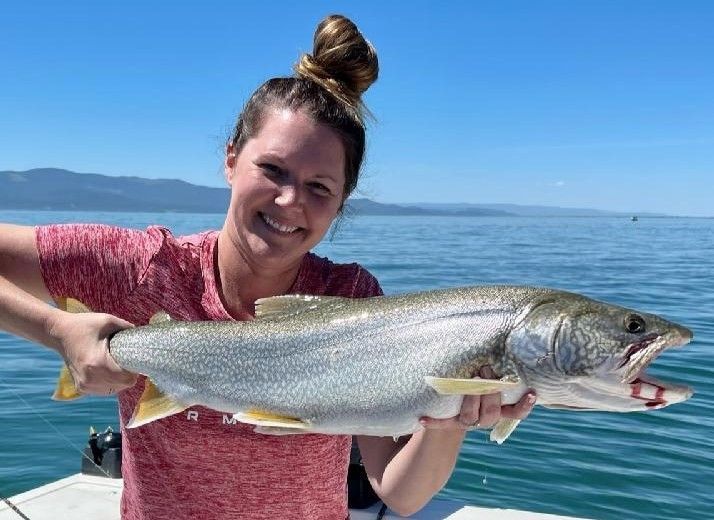 A woman is holding a large fish in her hands on a boat.