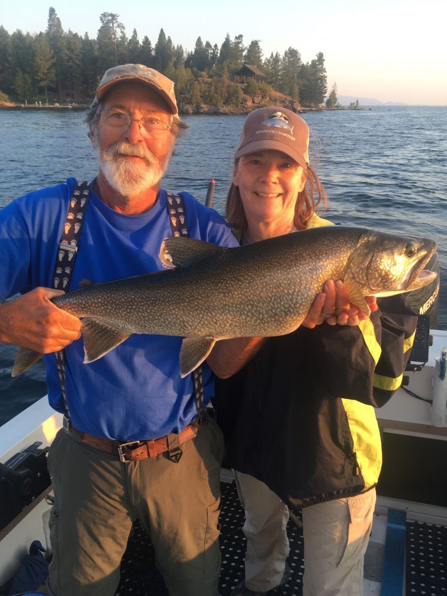 A man and woman holding a large fish on a boat