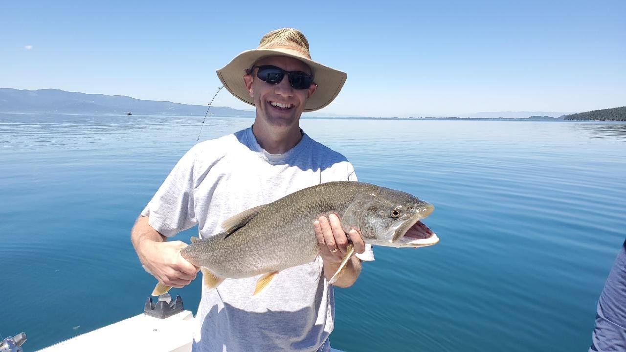 A man in a hat is holding a large fish in the water