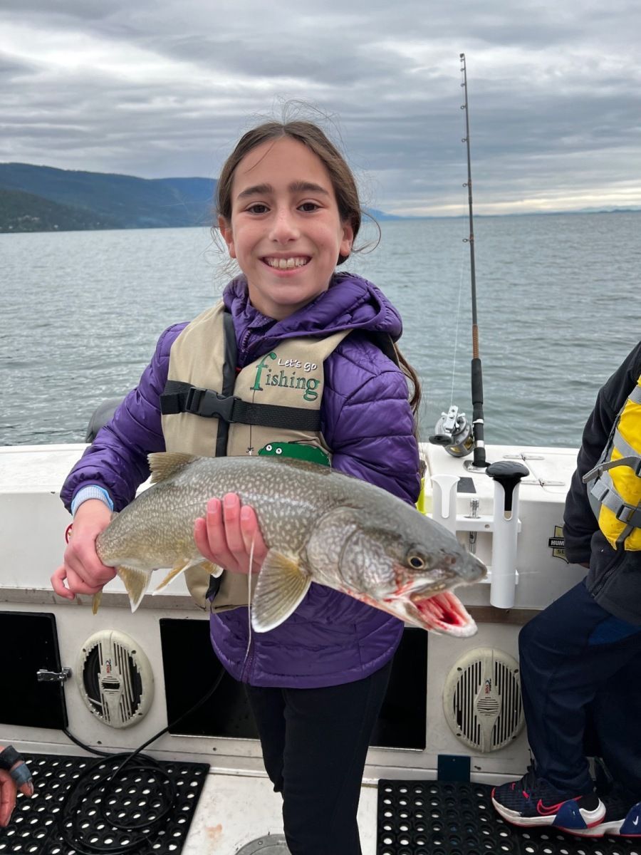 A young girl is holding a large fish on a boat.