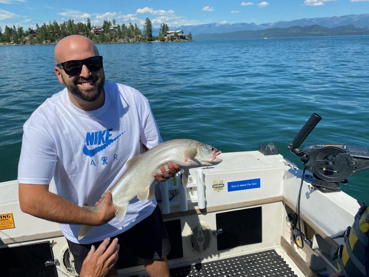 A man is holding a fish on a boat in the water.