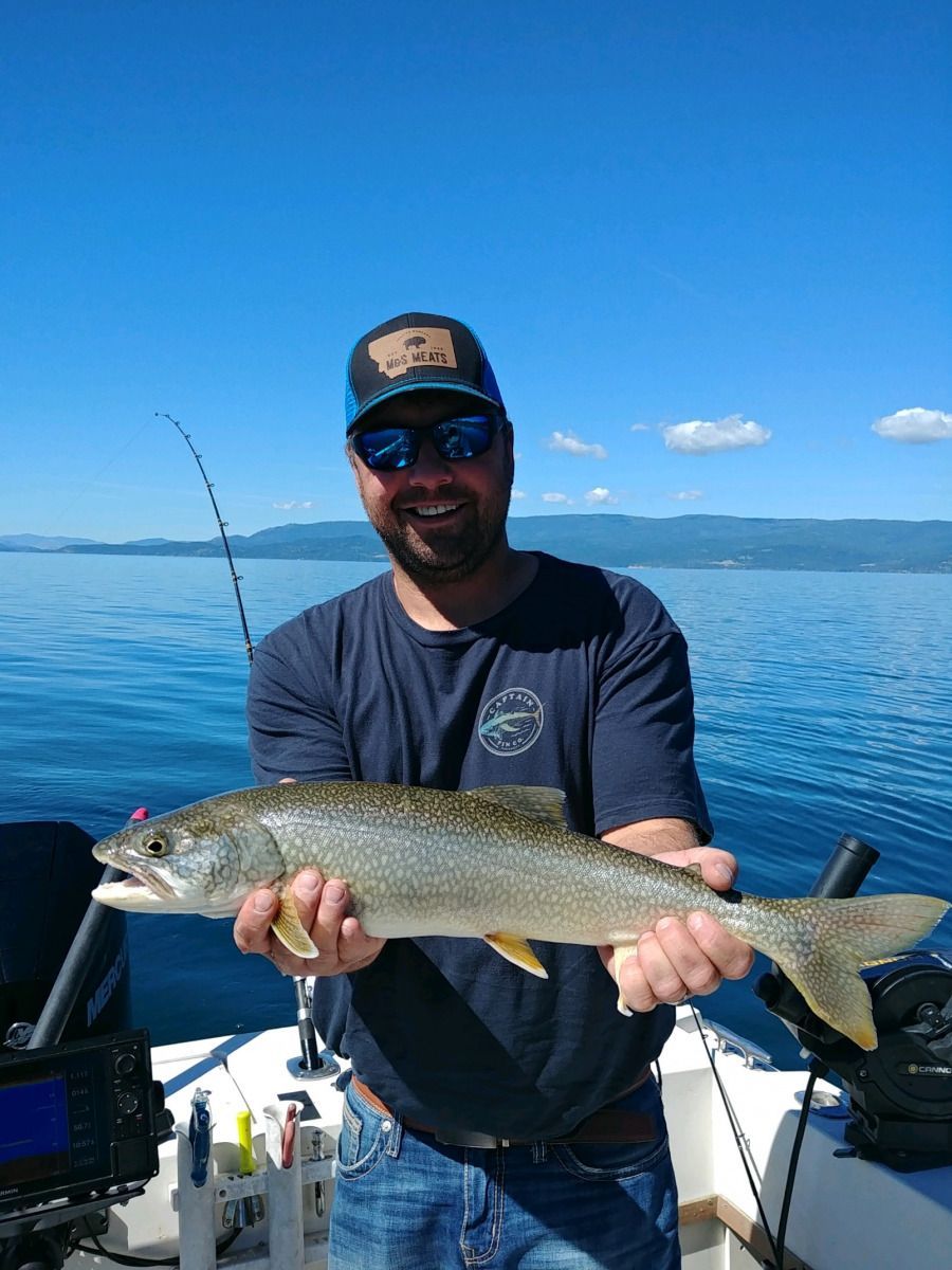A man is holding a fish on a boat in the water.