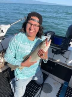 A man is kneeling on a boat holding a fish