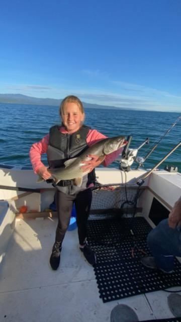 A young girl is holding a large fish on a boat.