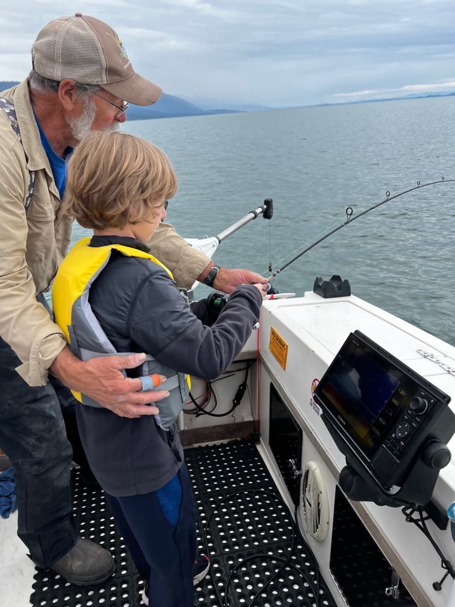 A man and a boy are fishing on a boat.