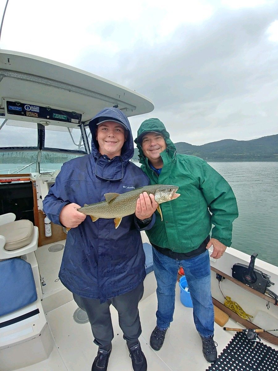 Two men are standing on a boat holding a fish.