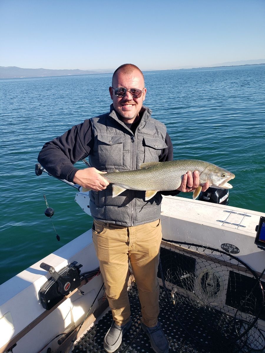 A man is holding a large fish on a boat in the water.