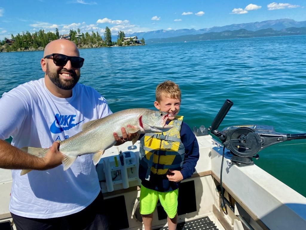 A man and a boy are standing on a boat holding a fish.