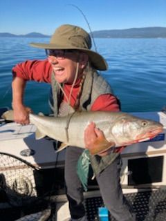 A man in a hat is holding a large fish on a boat