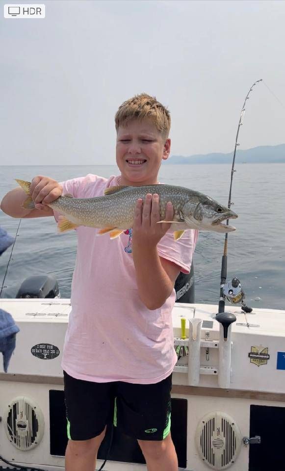 A young boy is holding a fish on a boat.