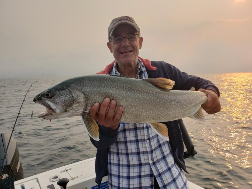 A man is holding a large fish on a boat.