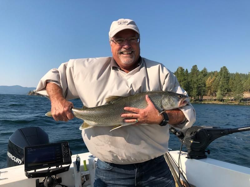 A man is holding a large fish on a boat.