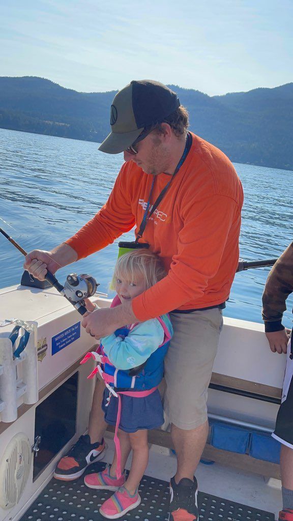A man and a little girl are fishing on a boat.