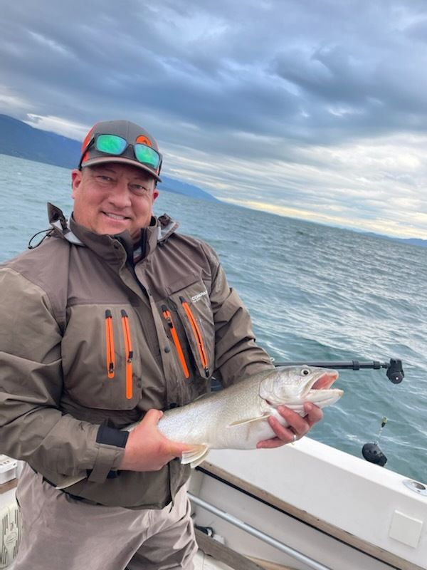 A man is holding a fish on a boat in the ocean