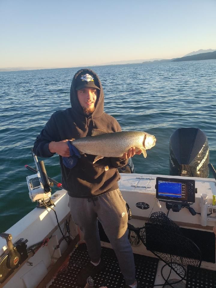 A man is holding a fish on a boat in the water.