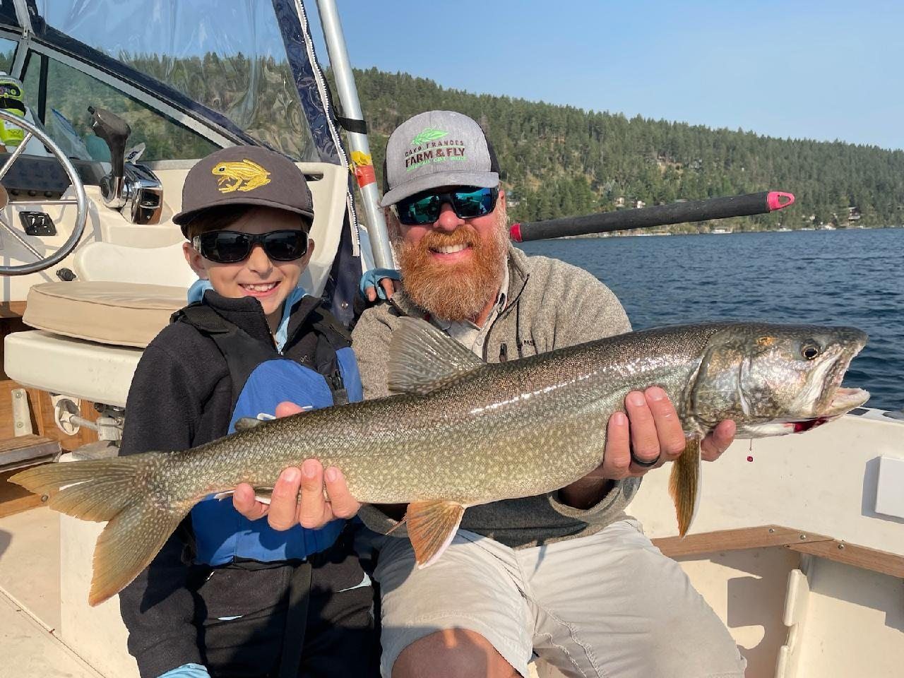 A man and a boy are sitting on a boat holding a large fish.