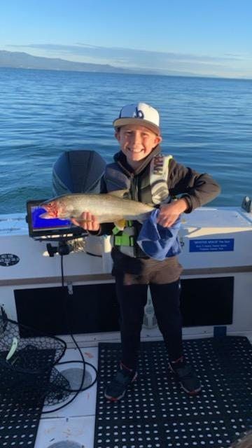 A young boy is holding a fish on a boat
