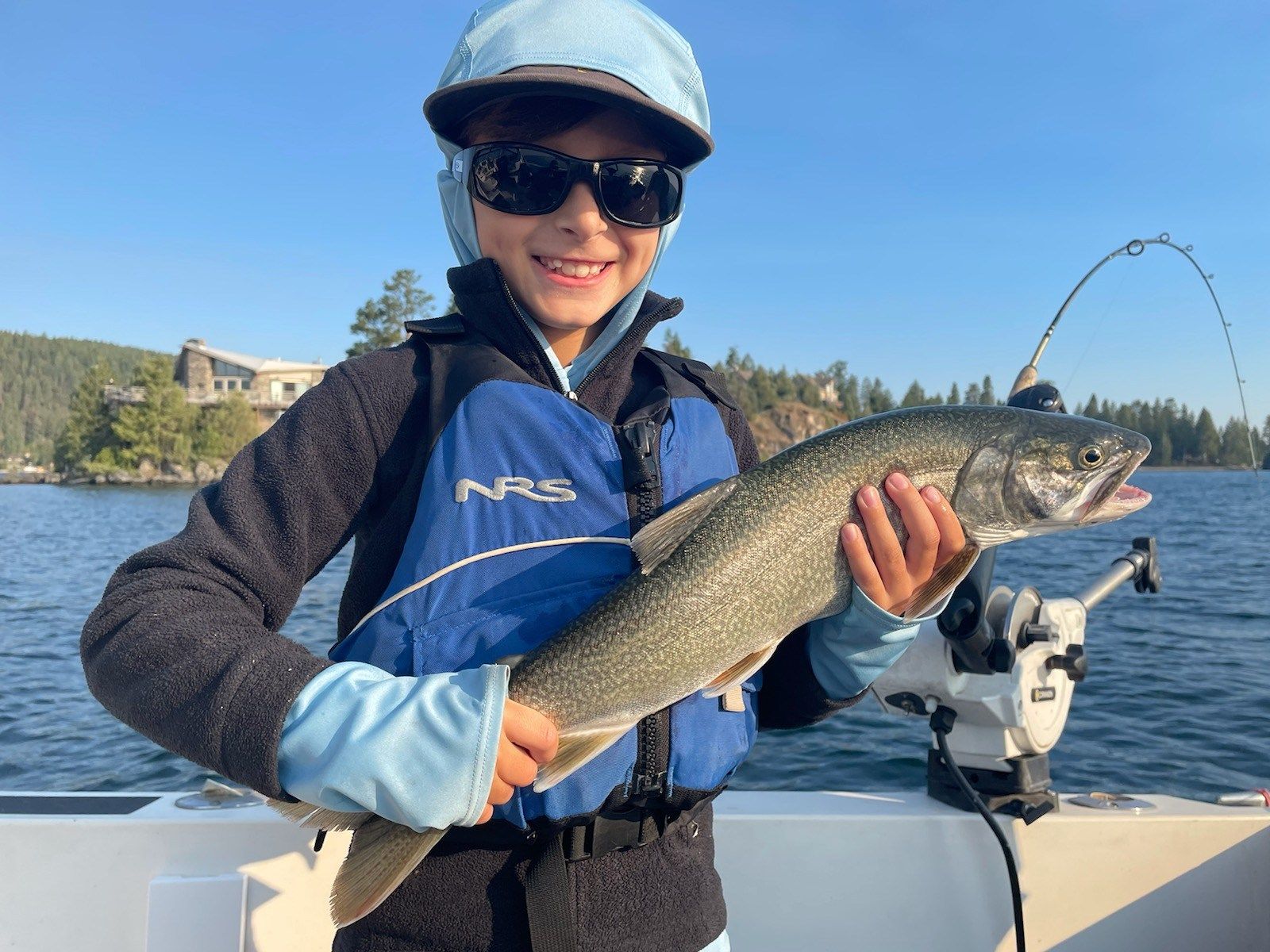 A young boy is holding a large fish on a boat.