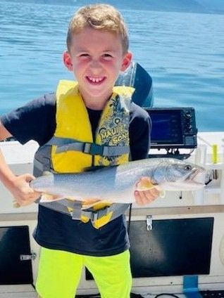 A young boy is holding a large fish on a boat.