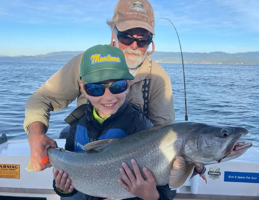 A man and a boy are holding a large fish on a boat.