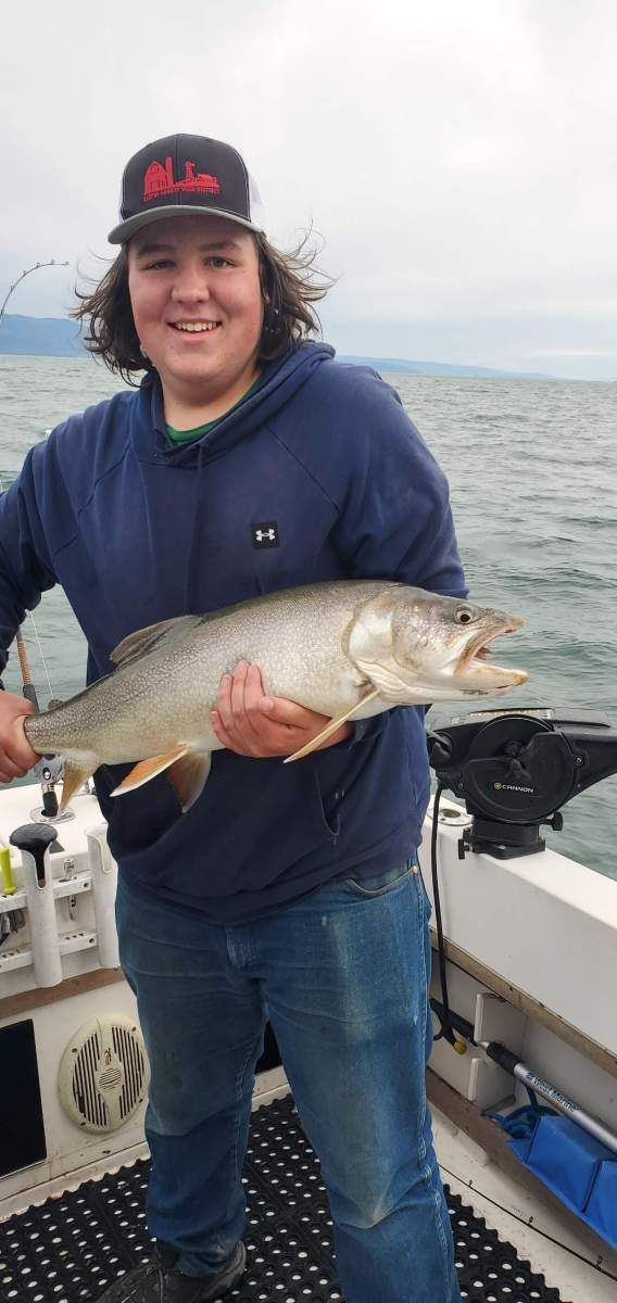 A young man is holding a large fish on a boat.