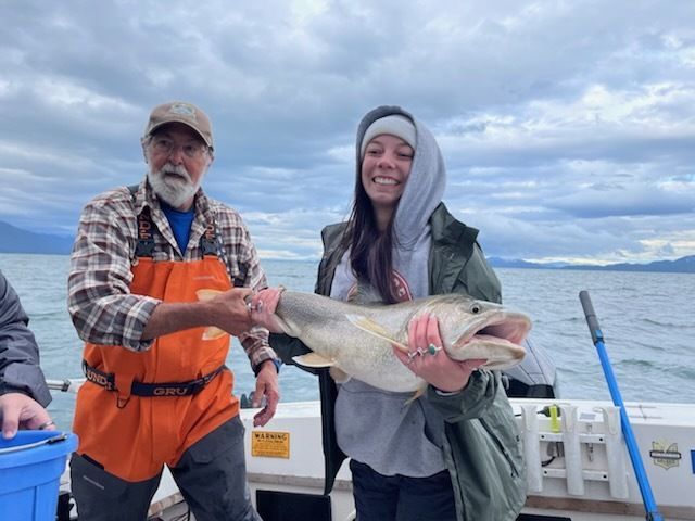 A man and a woman holding a large fish on a boat