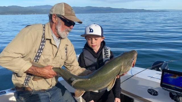 A man and a boy are holding a large fish on a boat.