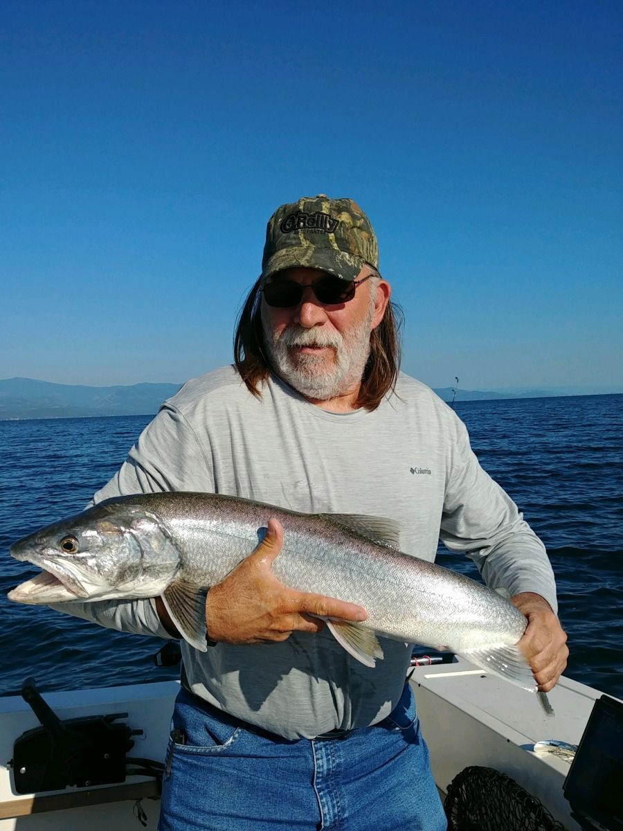 A man is holding a large fish in his hands on a boat.