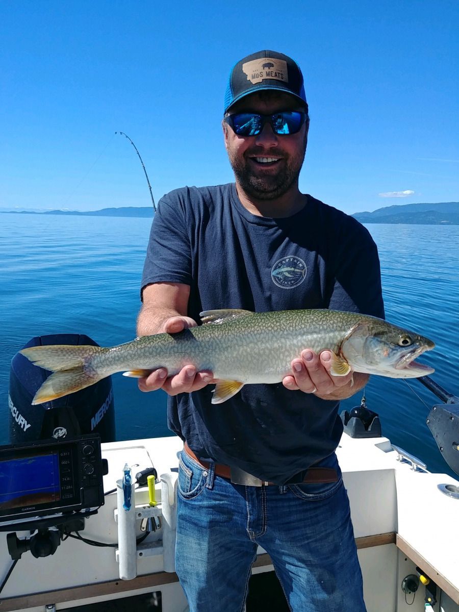 A man is holding a fish on a boat in the water.