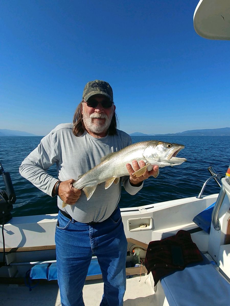 A man is holding a fish on a boat in the water.