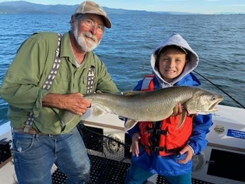 A man and a boy are holding a large fish on a boat.