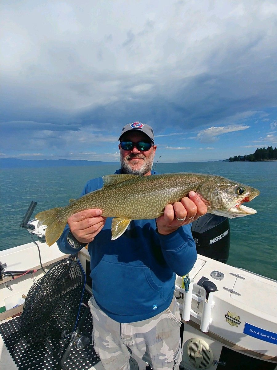A man is holding a fish on a boat in the water.