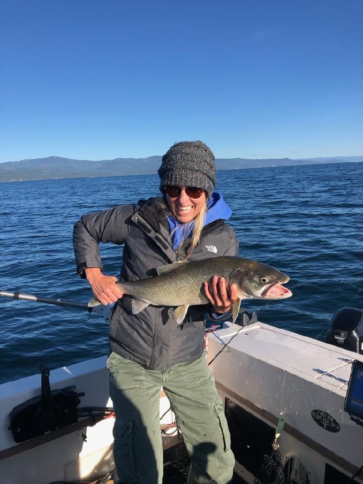 A woman is holding a fish on a boat in the water.