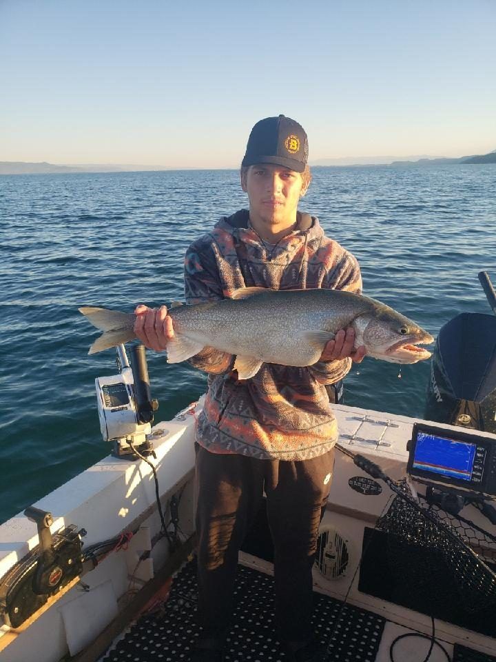 A young man is holding a large fish on a boat.