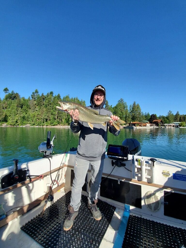 A man is standing on a boat holding a large fish.