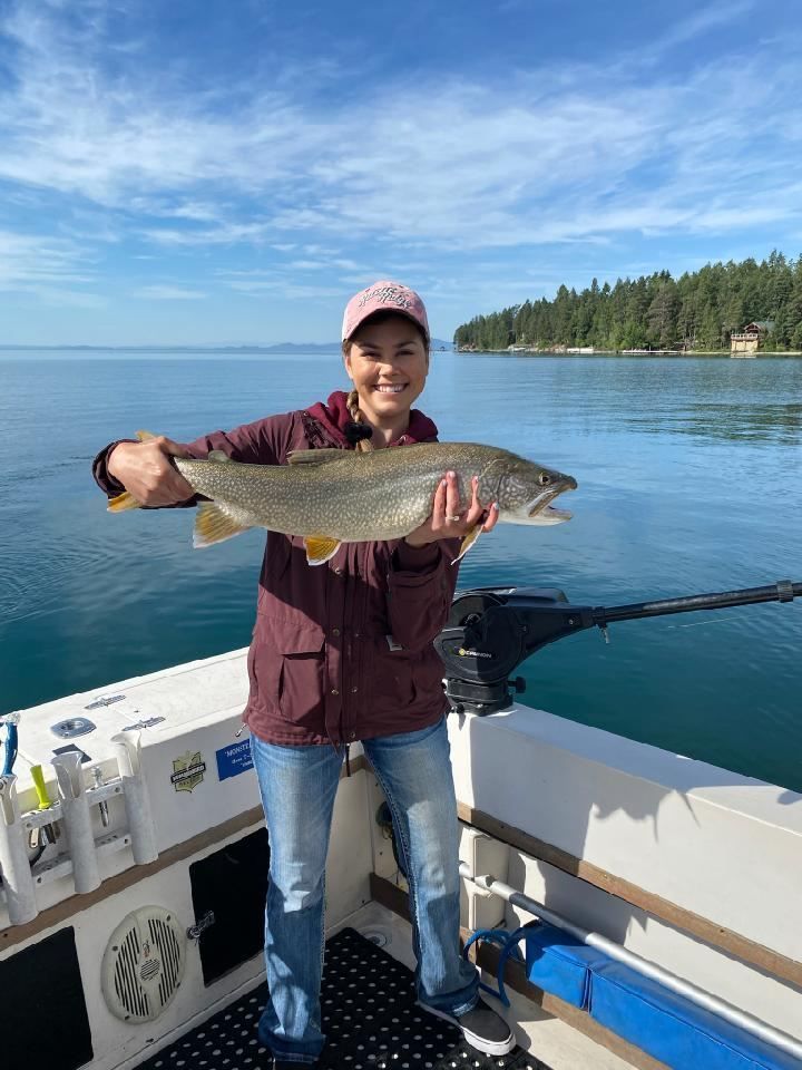 A woman is holding a large fish on a boat.