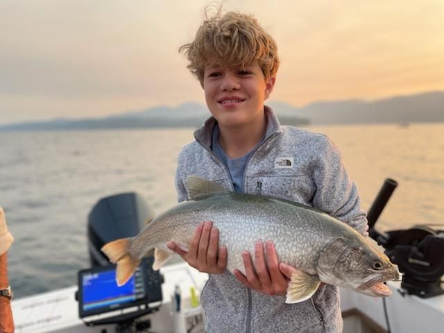 A young boy is holding a fish in his hands on a boat.