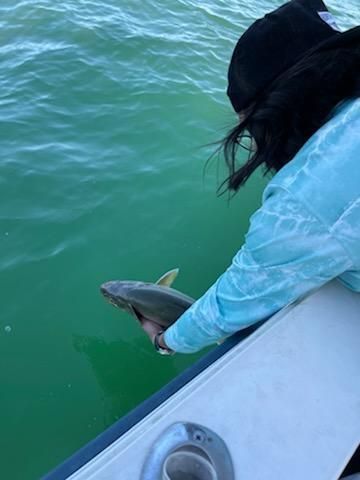 A woman is holding a fish on a boat in the water.