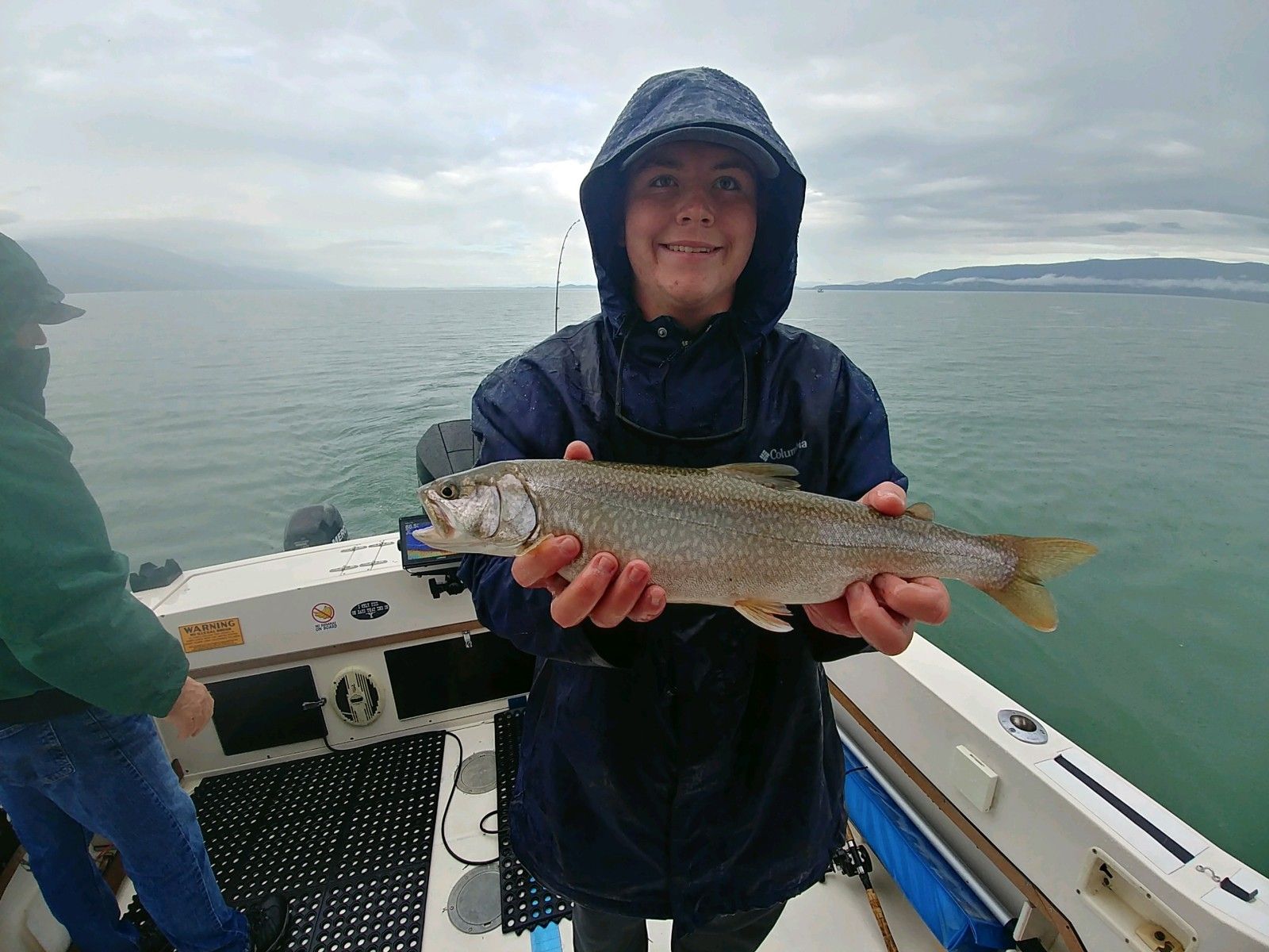 A person is holding a fish in their hands on a boat.
